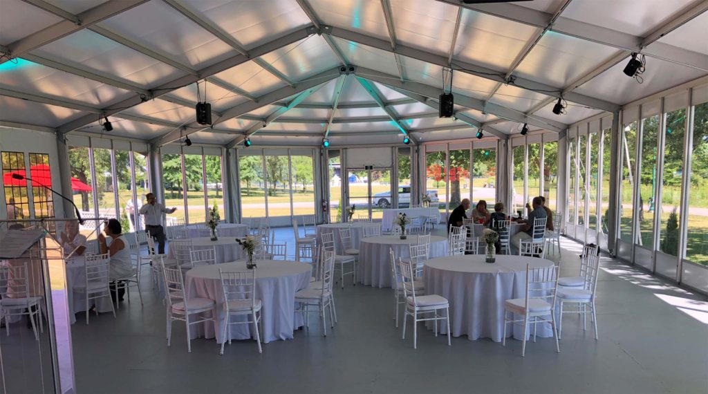 Wedding Tent Reception Interior with Glass Walls & Uplighting Glass-walled wedding structure tent interior with white chiavari chairs, round tables, and colorful uplighting