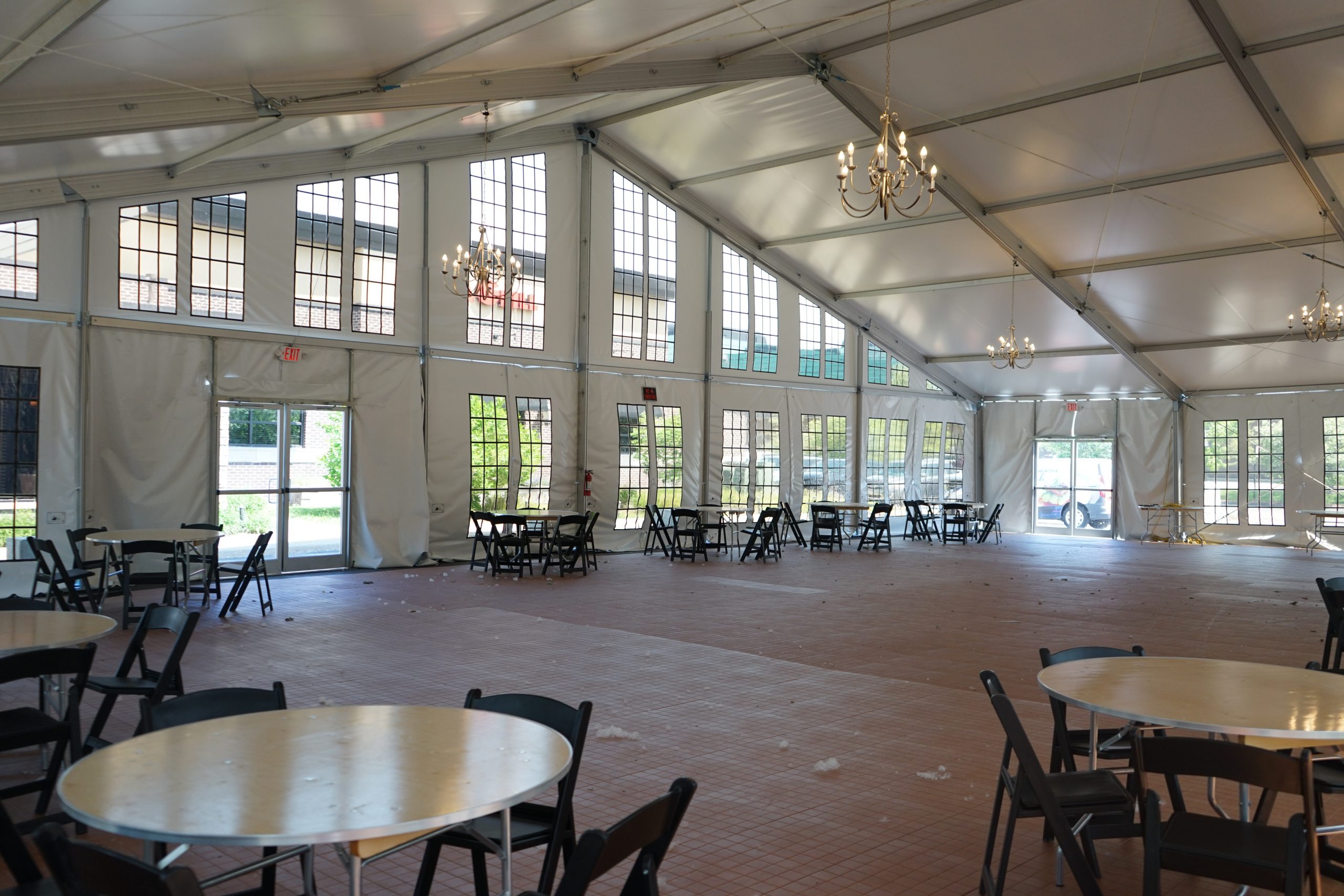 Interior of base camp dining hall tent with round tables, chairs, chandeliers, and floor-to-ceiling windows