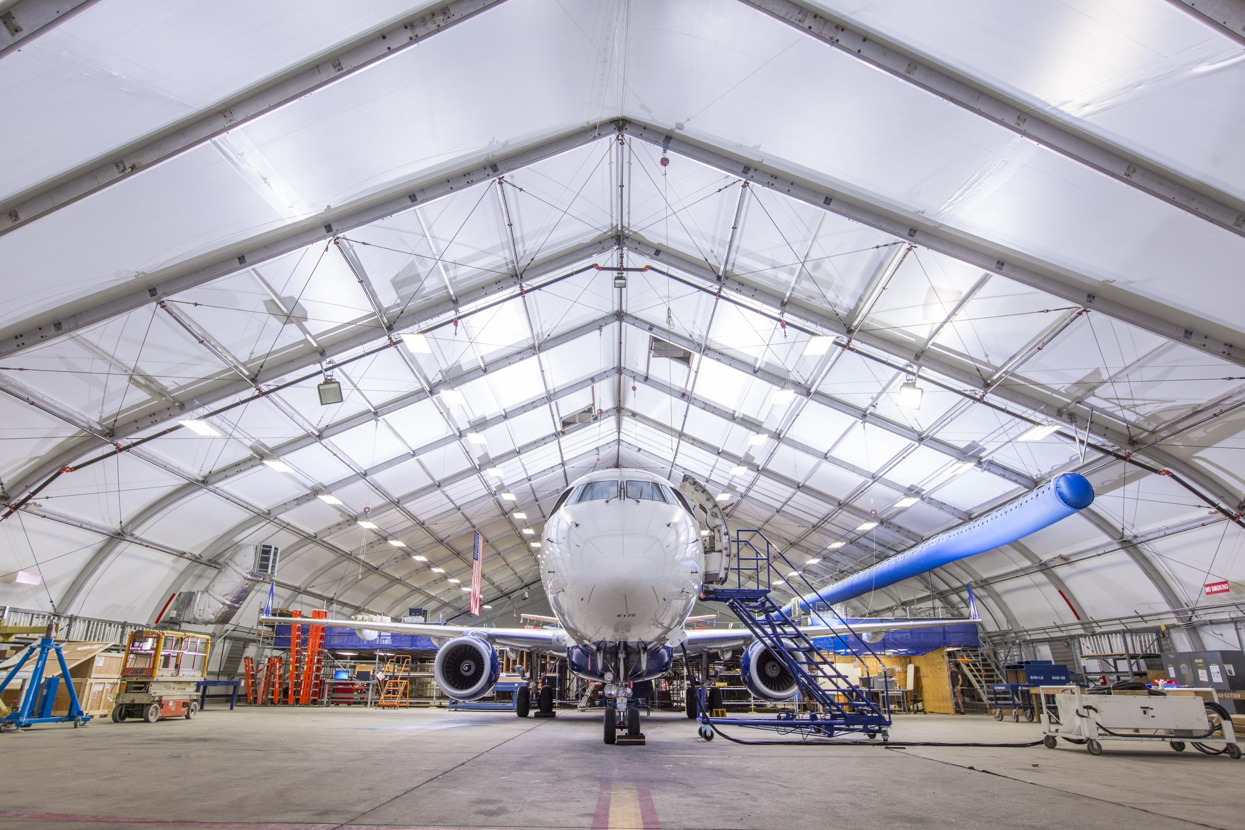 Aviation MRO Facility — Aircraft Maintenance Hangar Interior of temporary aviation hangar structure with commercial aircraft positioned for maintenance under translucent fabric roof panels