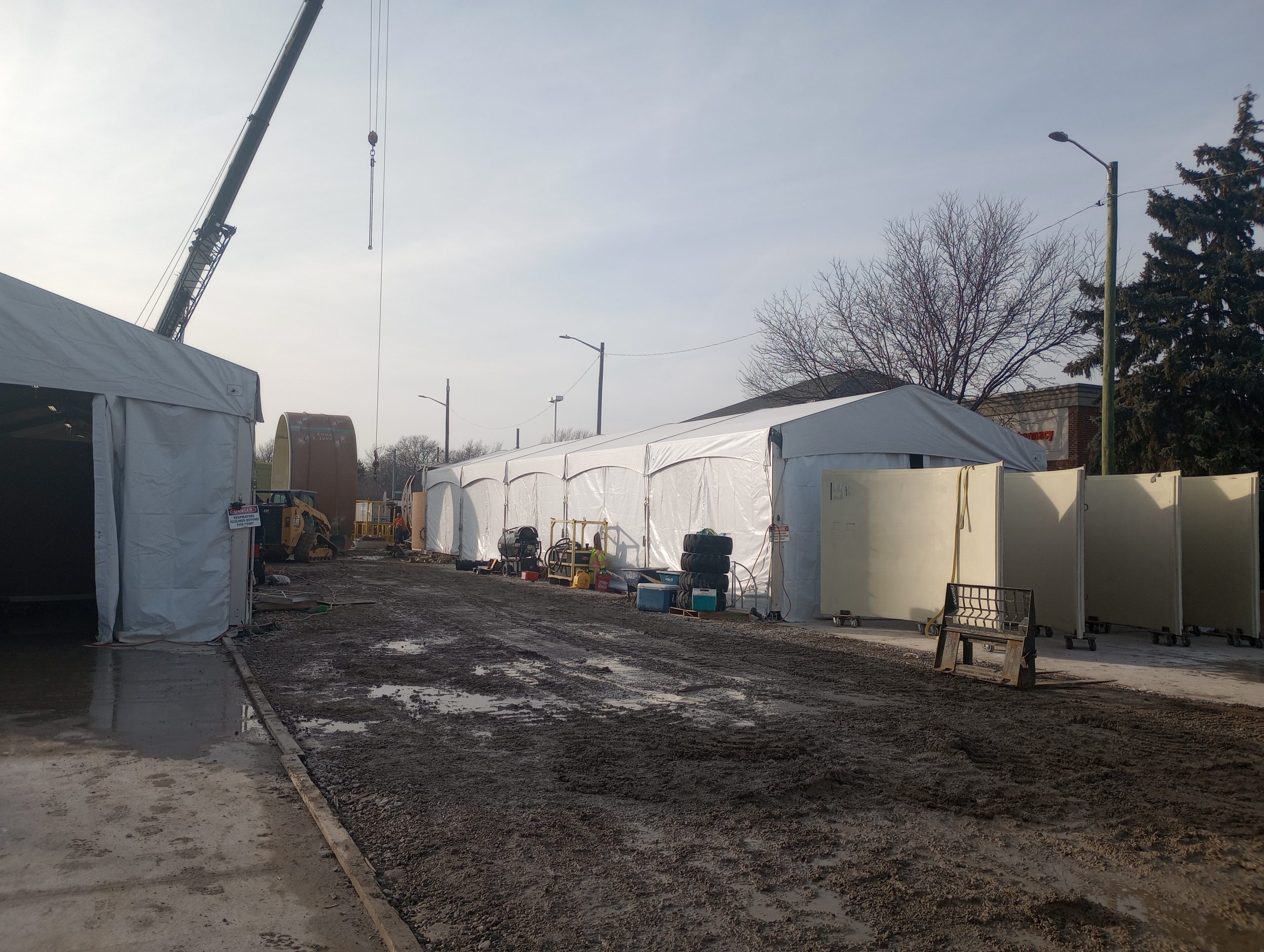 Multiple containment tent structures with crane on active restoration job site for hazardous material removal