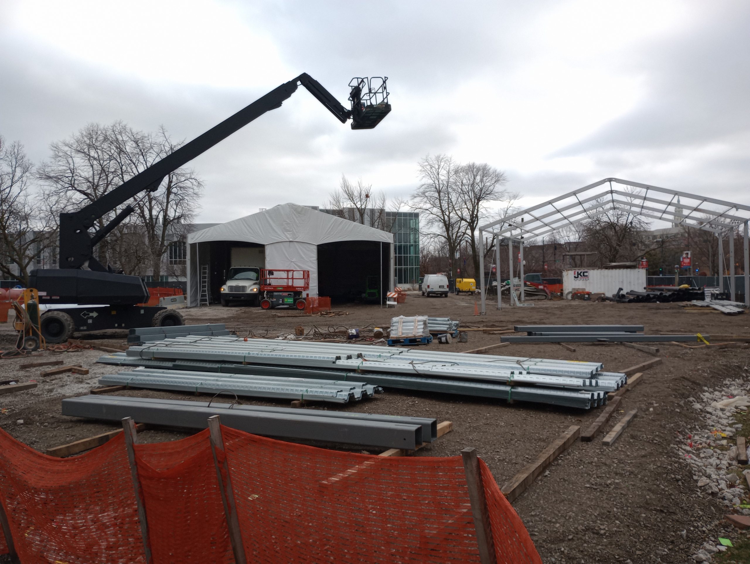 Active restoration job site with boom lift, tent structures, and aluminum framing being assembled