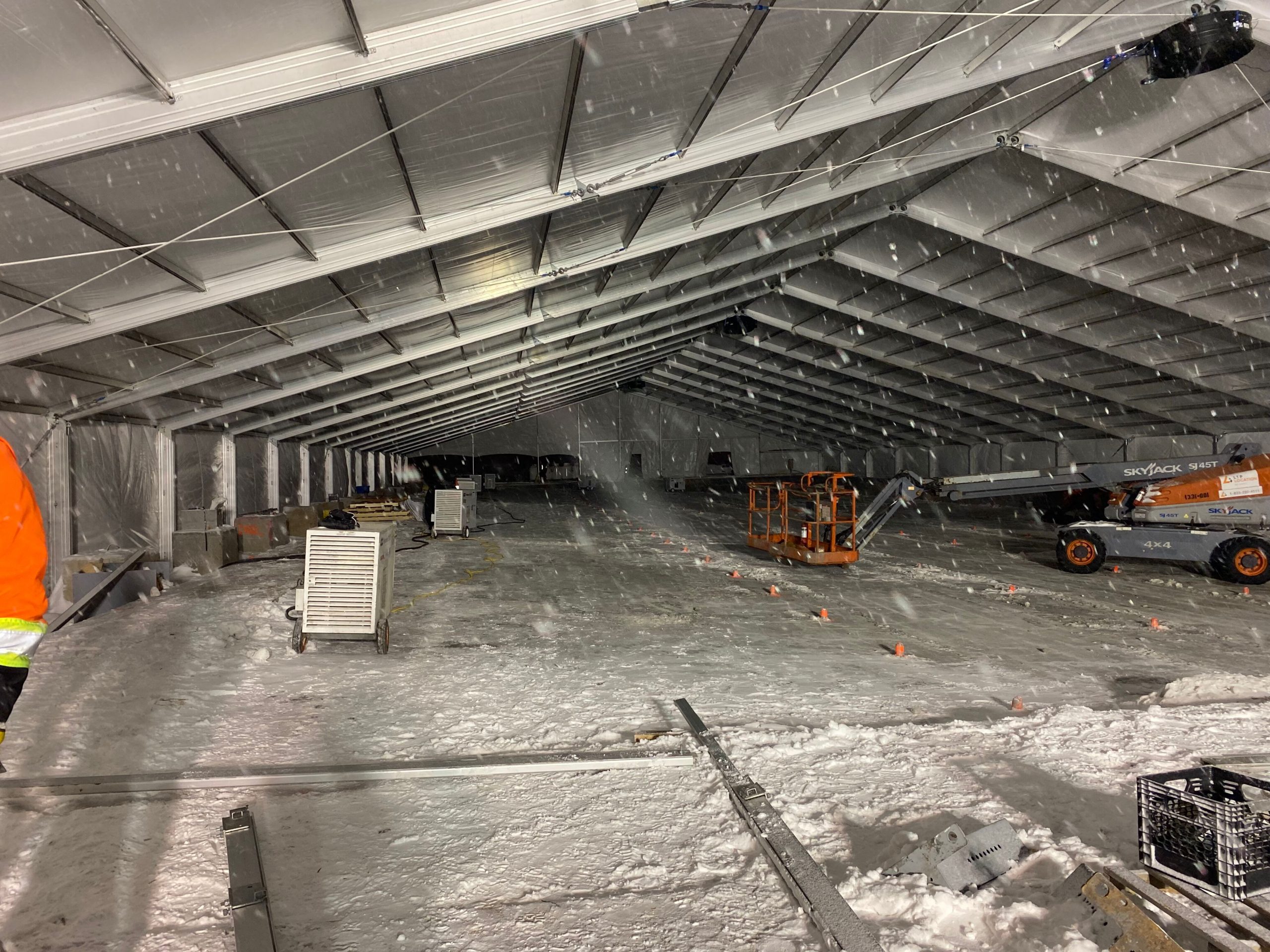 Interior of large building restoration tent structure with HVAC equipment and boom lifts for fire and water damage restoration