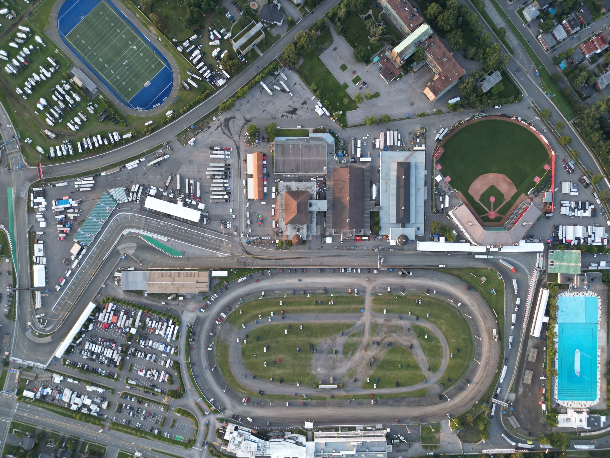 Aerial view of racing venue showing multiple grand stand structure tents with covered spectator seating and pit lane access