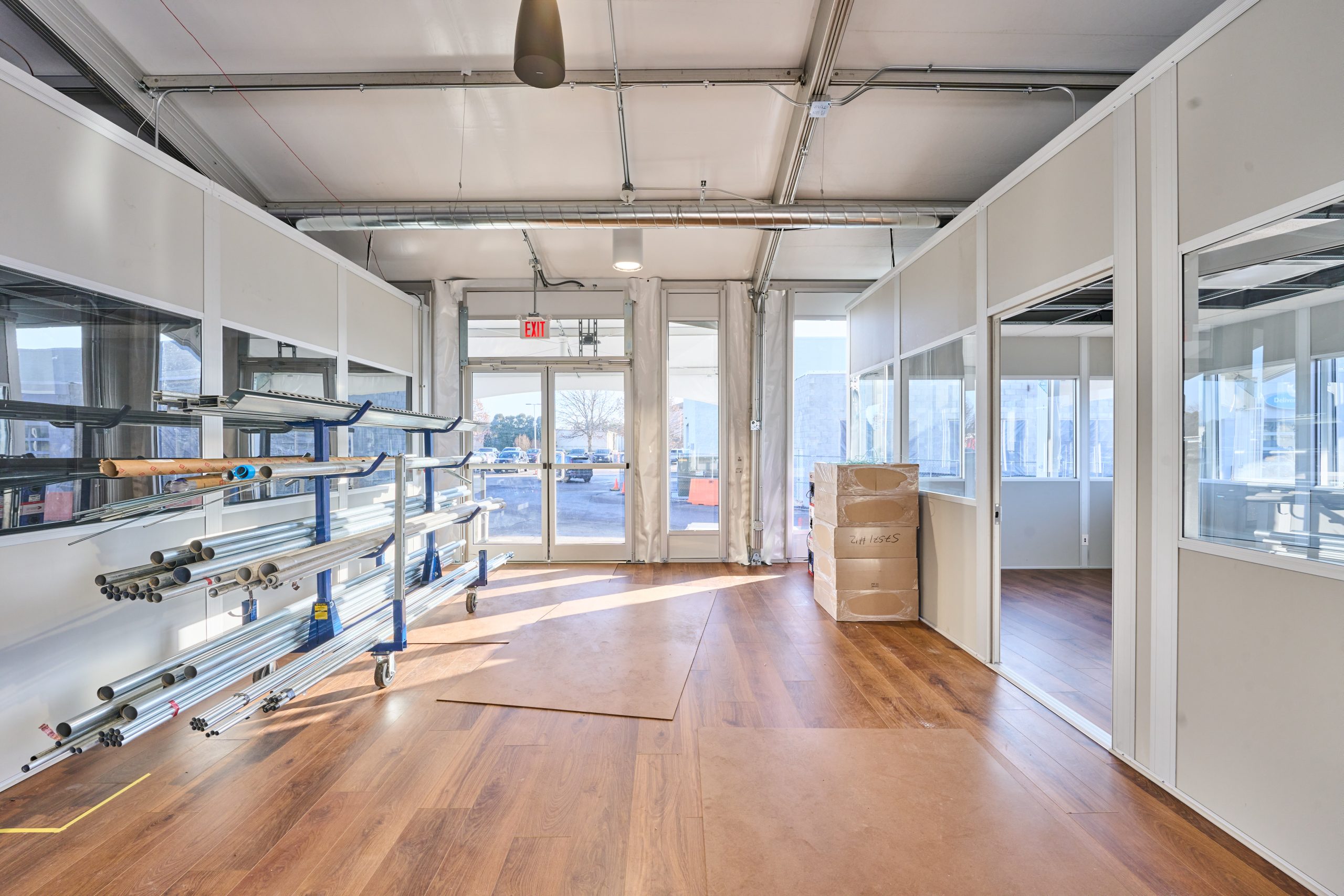 Temporary Structure Interior — Open Plan with Natural Lighting Interior of temporary structure with hardwood flooring, glass partitions, aluminum frame overhead, and natural light from glass walls